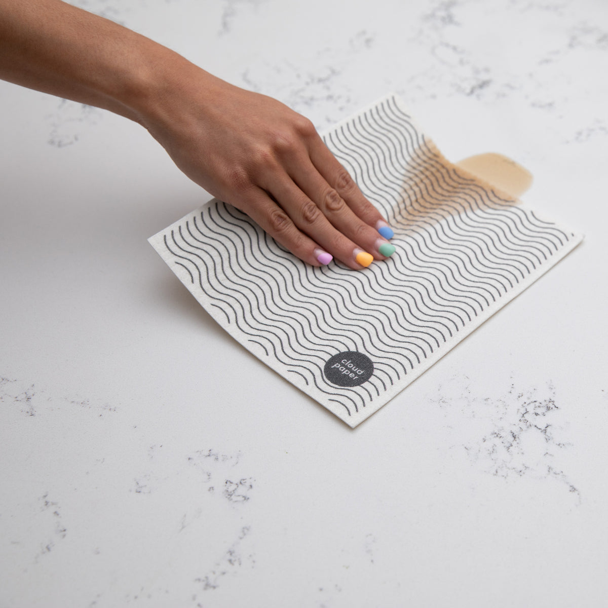 Swedish dishcloth wiping up a spill on a kitchen counter.